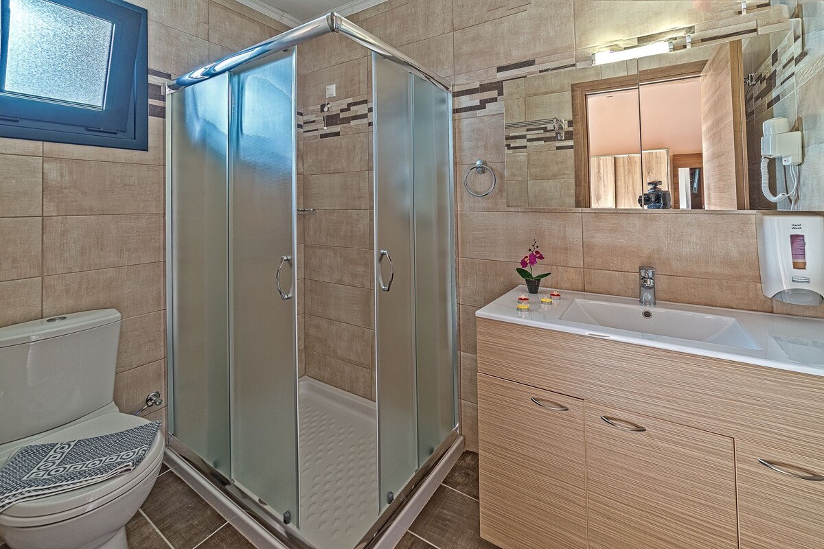 Een badkamer met een douche met glazen wand, een wit wastafelmeubel en een spiegel erboven.