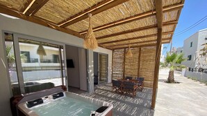 Un bain à remous sous une terrasse à toit de chaume, avec vue sur la rue.