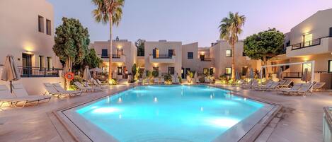 Een seizoensgebonden buitenzwembad, ligstoelen bij het zwembad