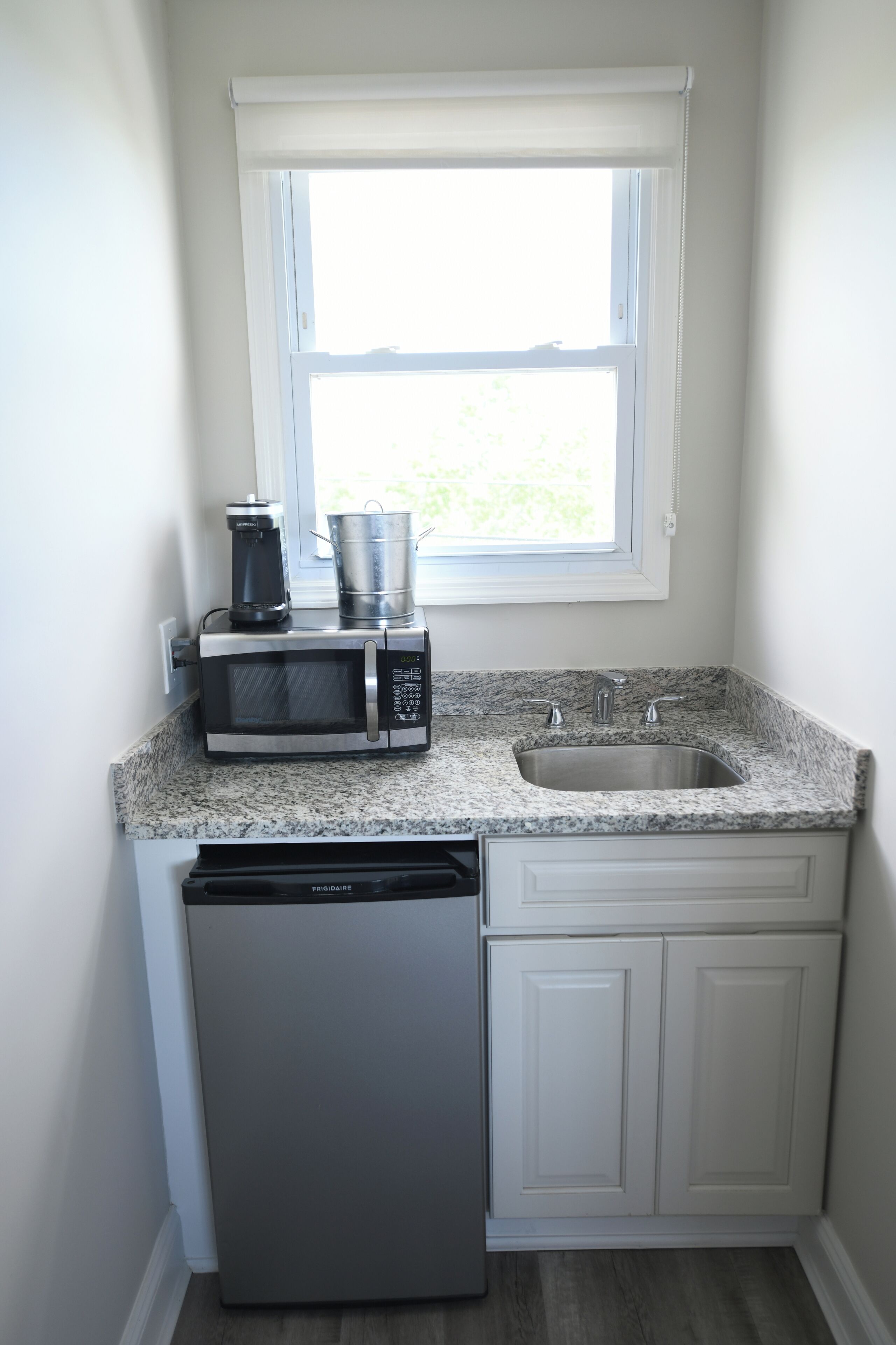 A compact kitchen with a built-in microwave, a coffee maker, and a sink.