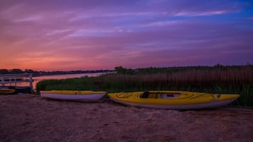 A beach with kayaks and a wooden dock.
