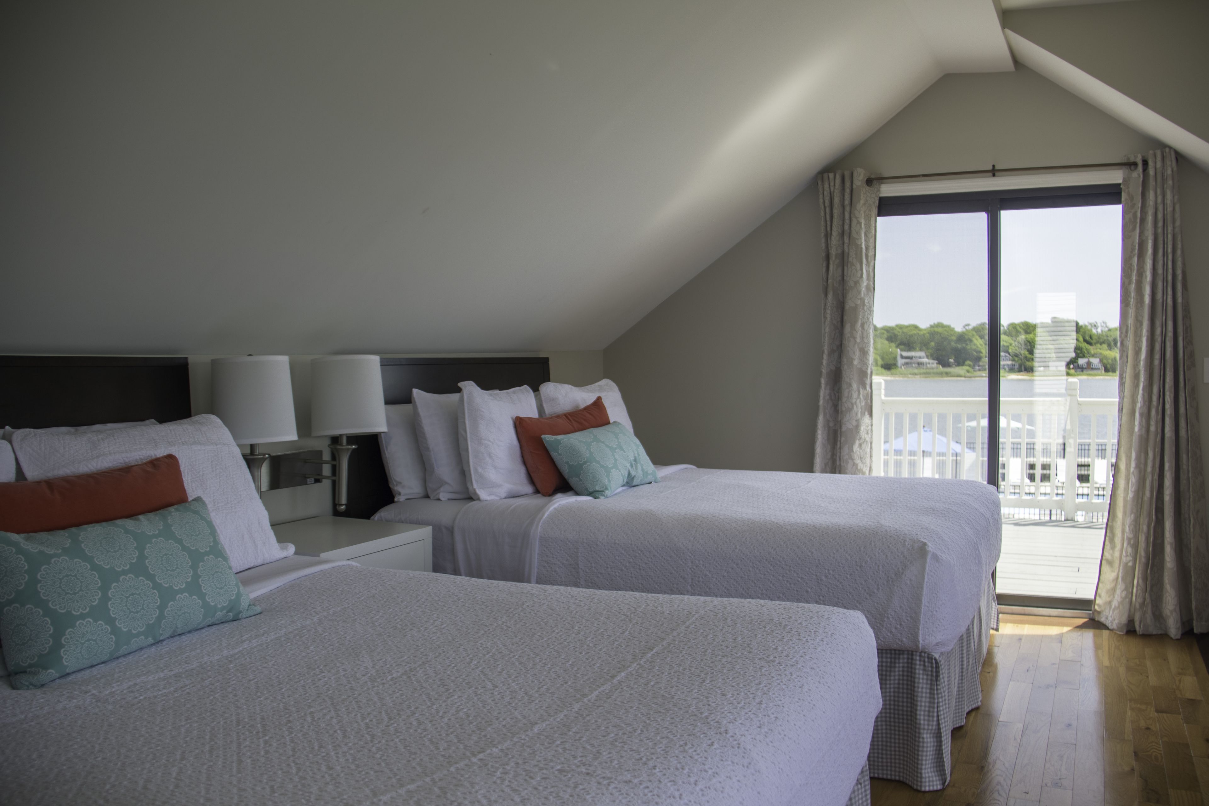 A hotel room with two beds, a nightstand, and a large window with curtains.