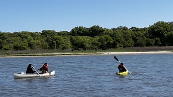 Two kayaks on calm water with a forested shoreline in the background.