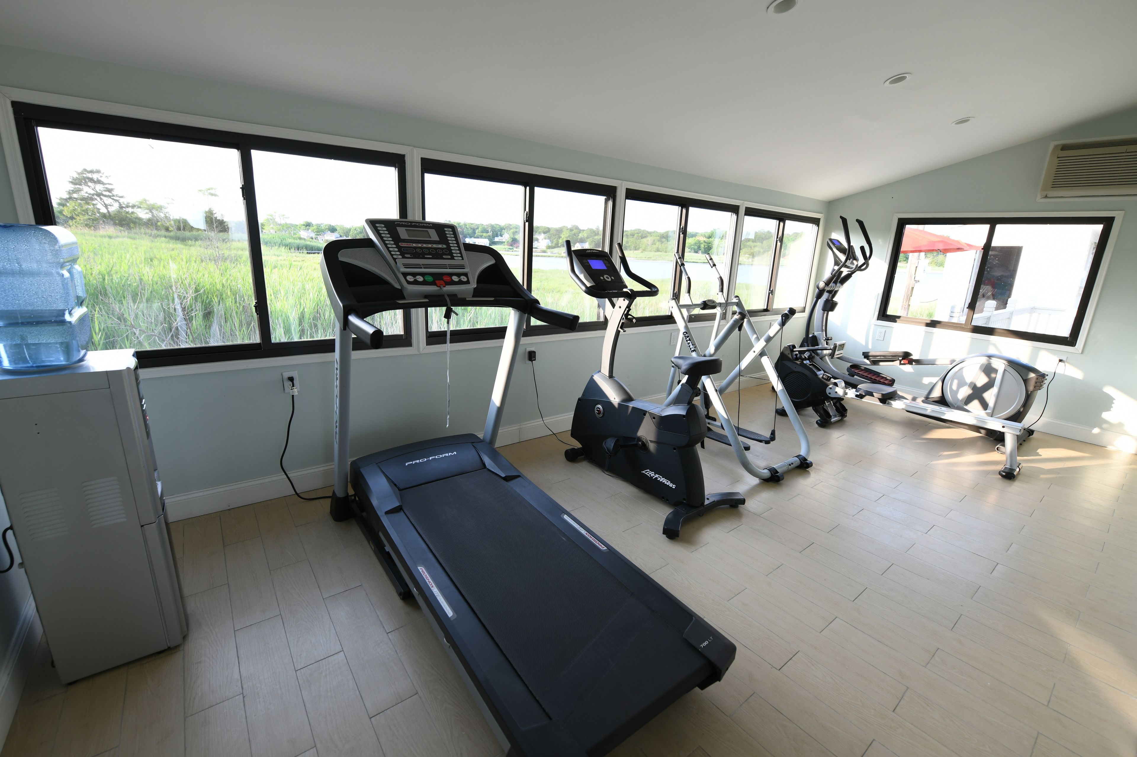 A gym with treadmills, elliptical machines, and a water cooler.