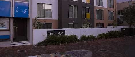 A multi-story building with the name "QUEST" on the facade, featuring a modern architectural style with large windows and a flat roof.