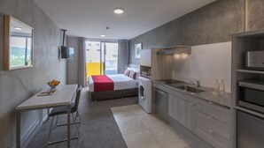 Une chambre d’hôtel compacte comprenant un lit, un lave-linge, une kitchenette et un coin repas.