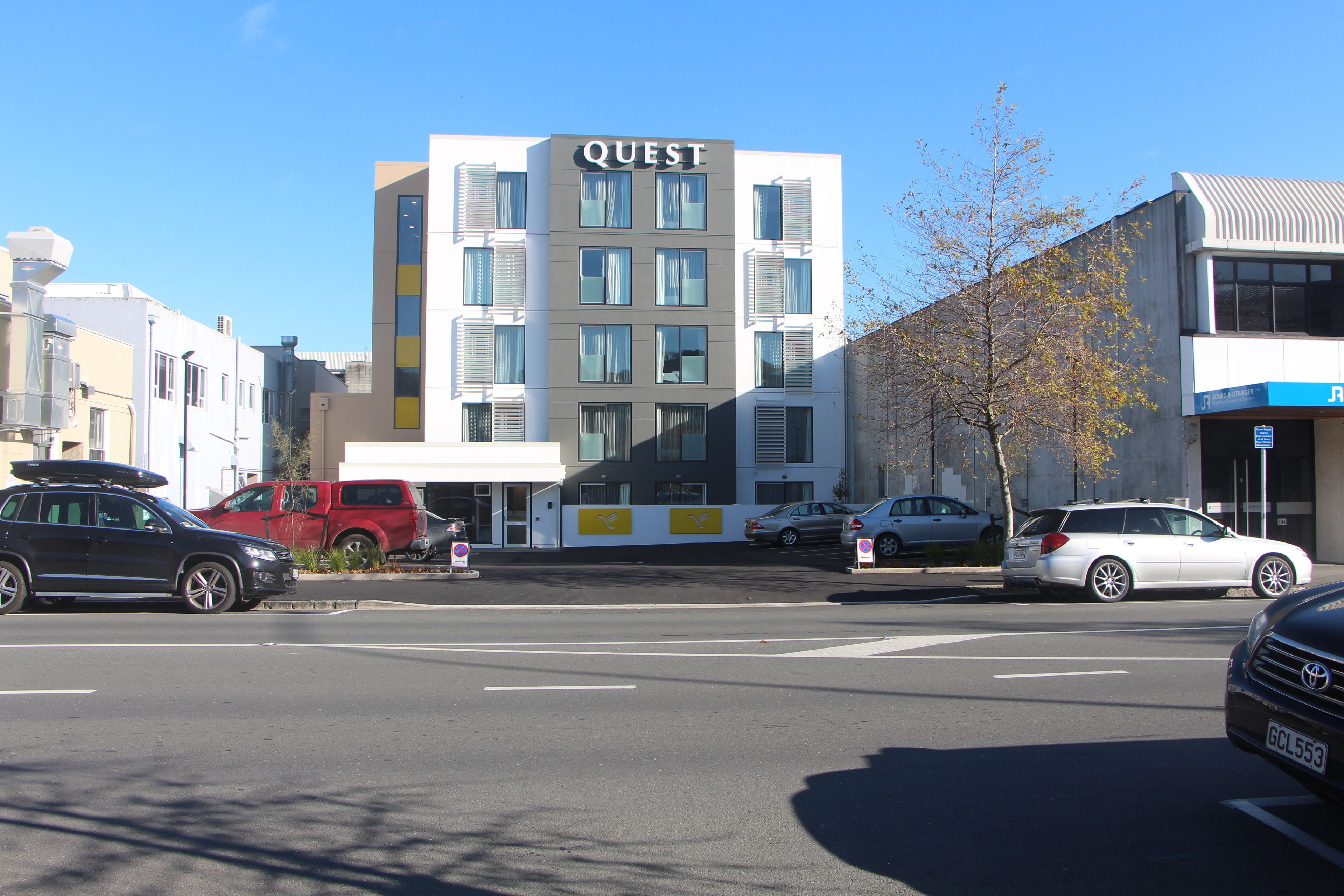 Un immeuble à plusieurs étages dont la façade porte une enseigne avec le mot « QUEST ».