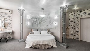 Un dormitorio con una cama grande, un tocador con espejo y una lámpara de pared.