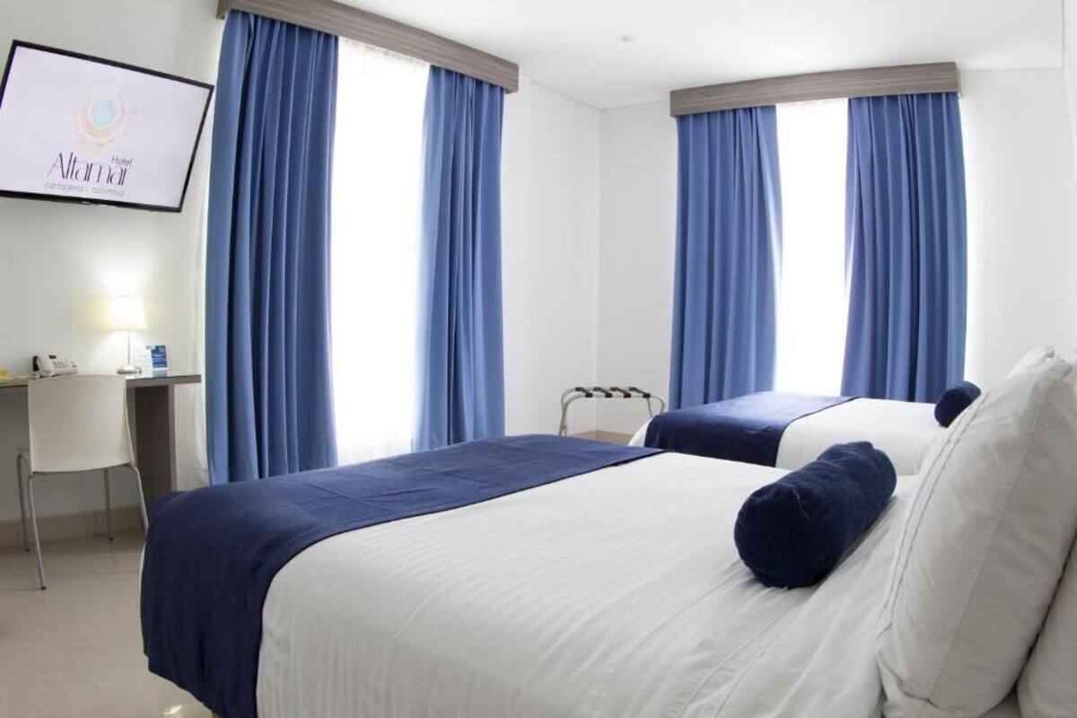 A hotel room with two beds, a desk, and a chair.