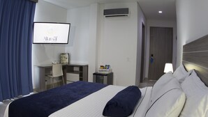 A hotel room with a bed, a desk, a TV, and an air conditioning unit. - Hotel Altamar (Cartagena)