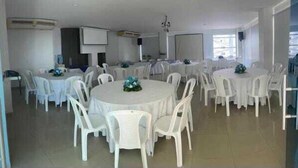 A spacious room with round tables and white plastic chairs, arranged for a gathering. - Hotel Altamar (Cartagena)