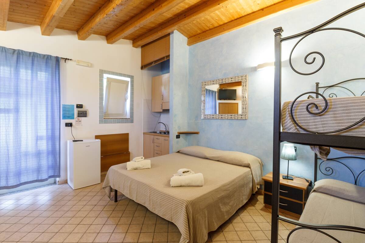 A bedroom with a bed, a bedside table, a mirror, a wardrobe, and a small desk.