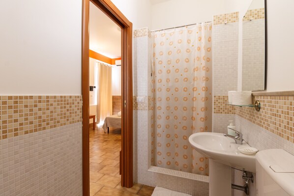 Un baño con ducha, lavamanos e inodoro.