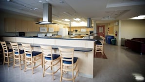 A modern kitchen with a central island, bar stools, and built-in appliances. - Grenfell Campus Summer Accommodations (Corner Brook)