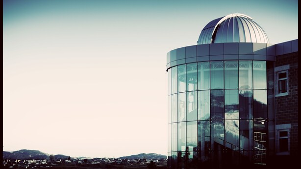 A modern building with a glass facade and a dome structure. - Grenfell Campus Summer Accommodations (Corner Brook)