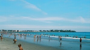 A crowded beach with people walking and swimming in the water. - Moulton Hotel (Hampton)