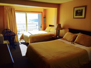 A hotel room with two beds, a desk, a chair, and a window with curtains. - Moulton Hotel (Hampton)