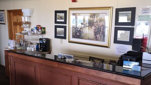 A reception desk with a coffee machine, a bulletin board with framed pictures, and a fire alarm on the wall. - Moulton Hotel (Hampton)