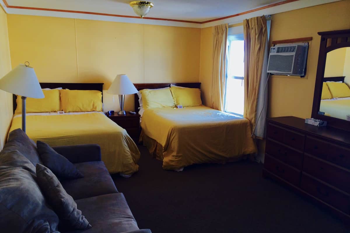 Een hotelkamer met twee bedden, een bank, een dressoir en een plafondventilator.