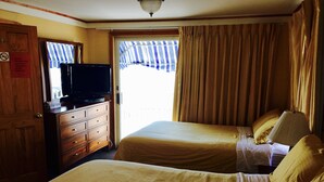 A hotel room with two beds, a wooden dresser, a television, and a window with curtains. - Moulton Hotel (Hampton)