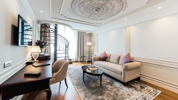 A modern living room with a sofa, coffee table, and a desk with a lamp. - Arcade Hotel (Istanbul)