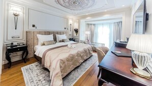 A spacious bedroom with a large bed, a desk, and a vanity with a mirror. - Arcade Hotel (Istanbul)