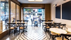 A restaurant interior with hexagonal patterned flooring, round tables, and black chairs. - Arcade Hotel (Istanbul)