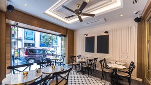 A restaurant with round tables and chairs, a ceiling fan, and a view of the street outside. - Arcade Hotel (Istanbul)