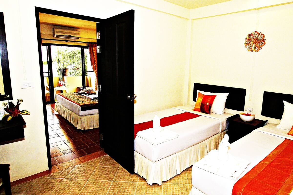 A hotel room with two beds, a bathroom, and a view of the outside.