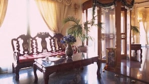 A room with a wooden sofa, a table with a vase, and a large window with curtains. - Hotel Geo (Rome)