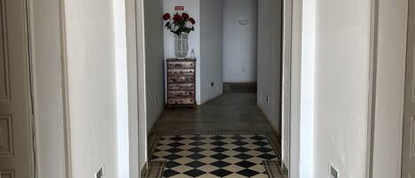 A hallway with a black and white checkered floor, white walls, and an arched ceiling.