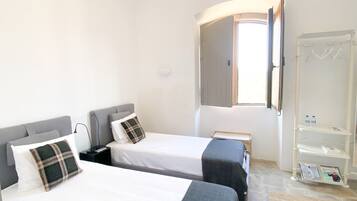A bedroom with two beds, a wardrobe, and a window.