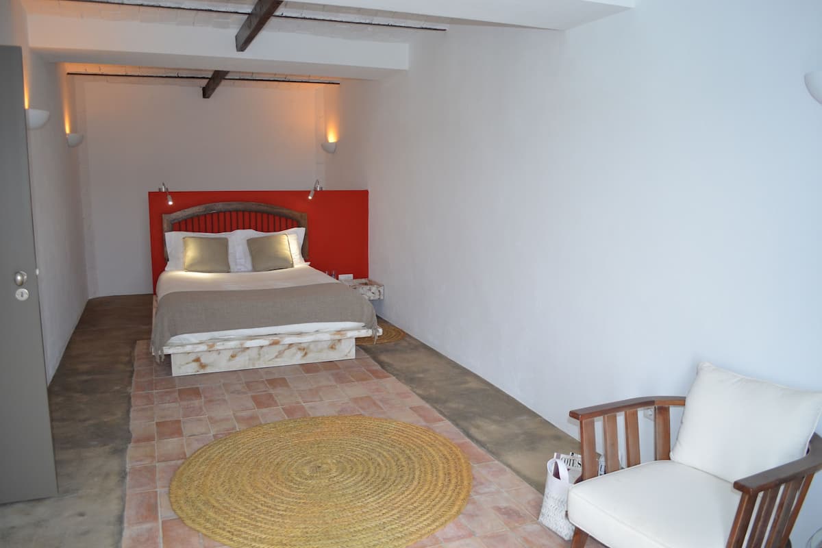 A bedroom with a bed, a chair, and a wall-mounted lamp.