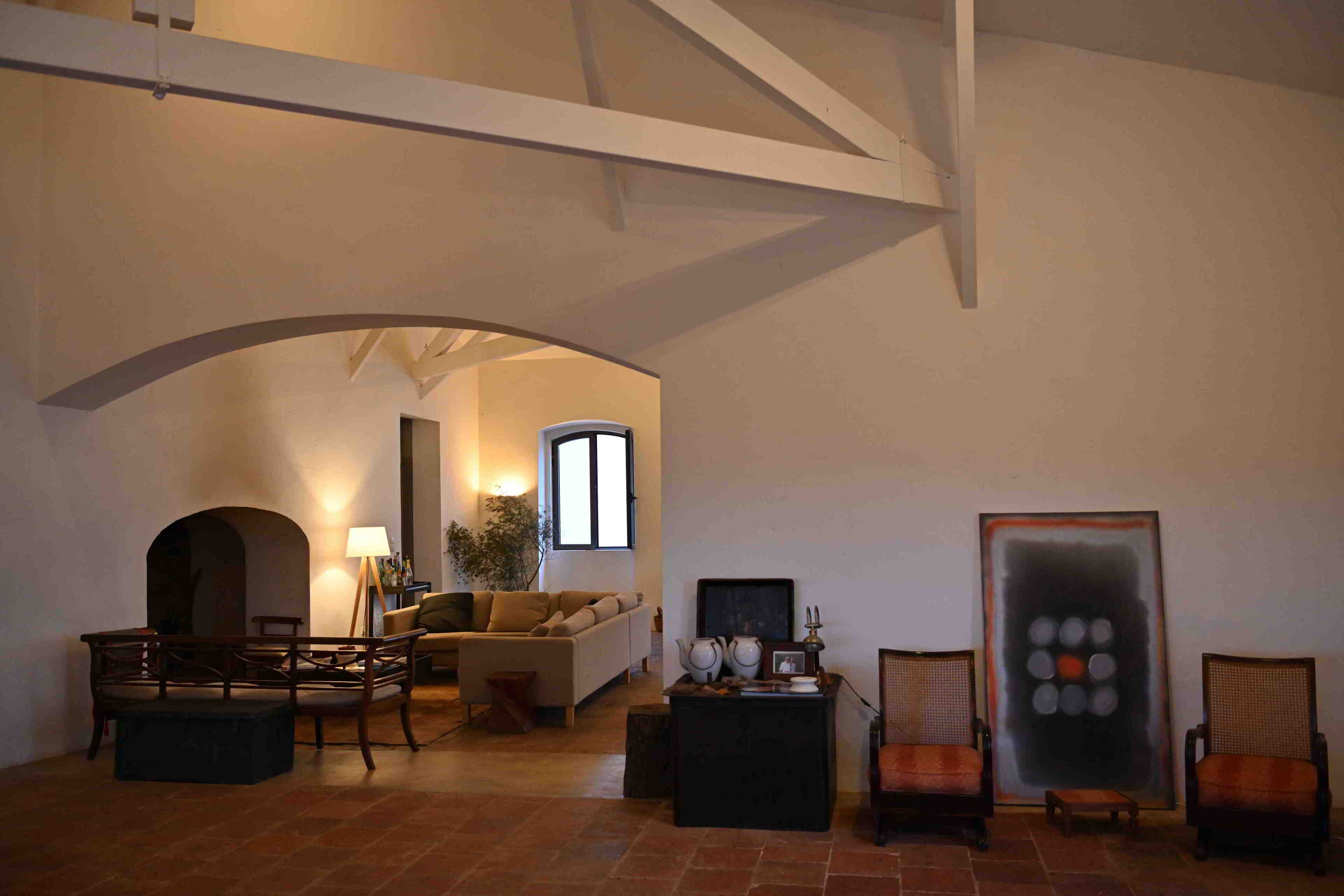 Een ruime woonkamer met een hoge plafond, een bank, fauteuils, een salontafel en een groot abstract schilderij.