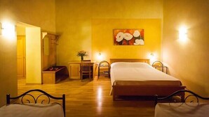 A room with two beds, wooden flooring, a desk, a chair, and a painting on the wall.