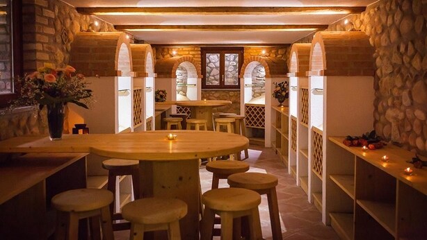 A cozy dining area with stone walls, wooden tables, and stools.