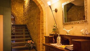 A staircase with stone walls, a wooden handrail, and a small table with a vase of flowers.