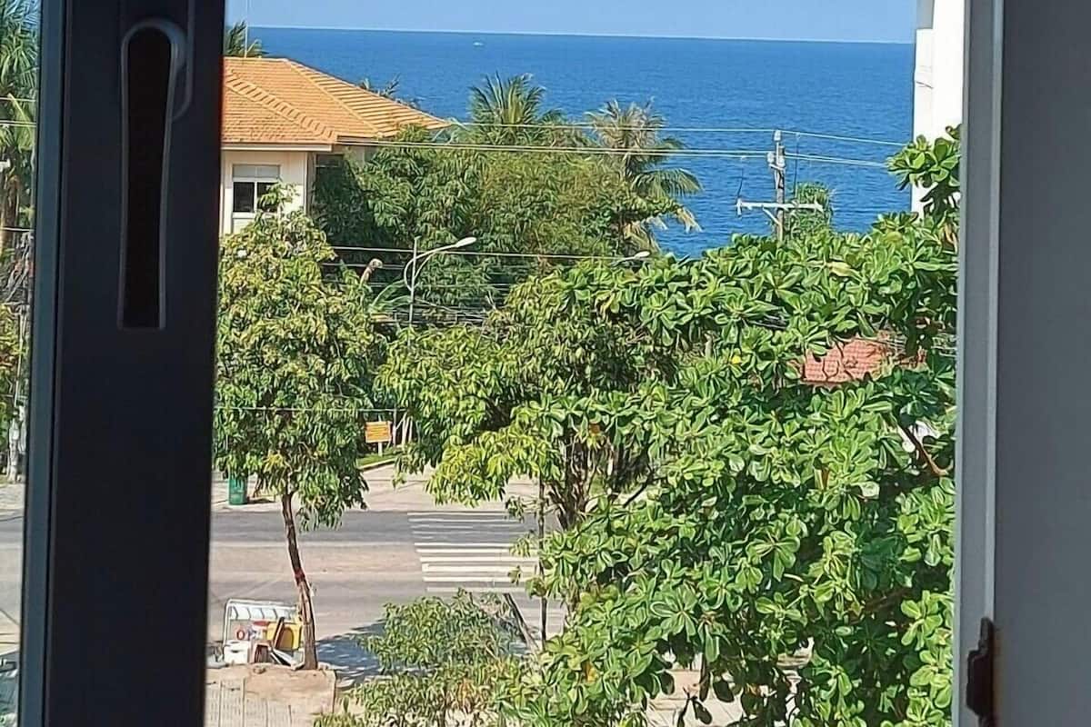 A view from a window overlooking a street with buildings and a clear blue sky.