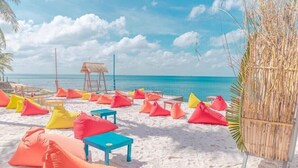 A beach with colorful bean bags and a thatched hut. - Victoria Phu Quoc Hotel (Phu Quoc)