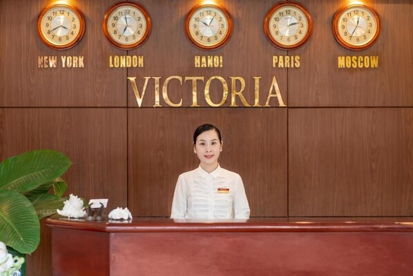 A reception desk with clocks displaying times from New York, London, Hanoi, Paris, and Moscow. - Victoria Phu Quoc Hotel (Phu Quoc)