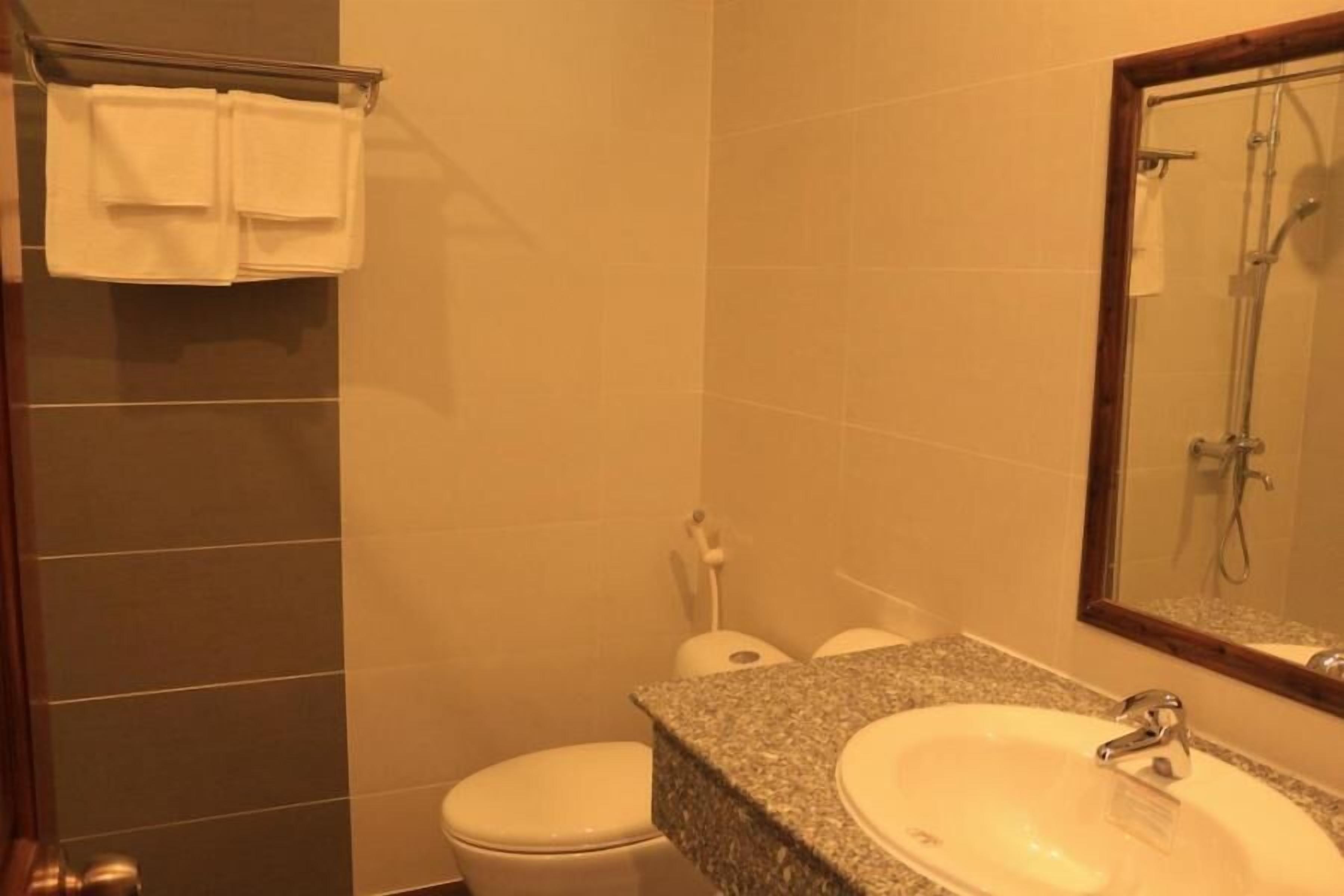 Un baño con lavamanos y encimera de granito, inodoro y ducha.