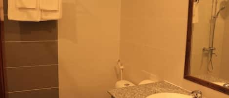 Un baño con lavamanos y encimera de granito, inodoro y ducha.