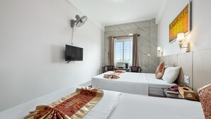 A hotel room with two beds, a flat-screen TV, a desk with a chair, a window with curtains, and a painting on the wall. - Victoria Phu Quoc Hotel (Phu Quoc)