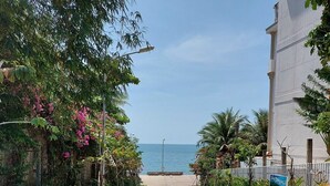 A paved pathway leading to a beach, flanked by lush greenery and a building with a white facade. - Victoria Phu Quoc Hotel (Phu Quoc)