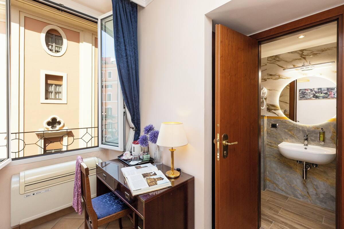Une chambre d’hôtel équipée d’un bureau, d’une chaise et offrant une vue sur la ville par une fenêtre.
