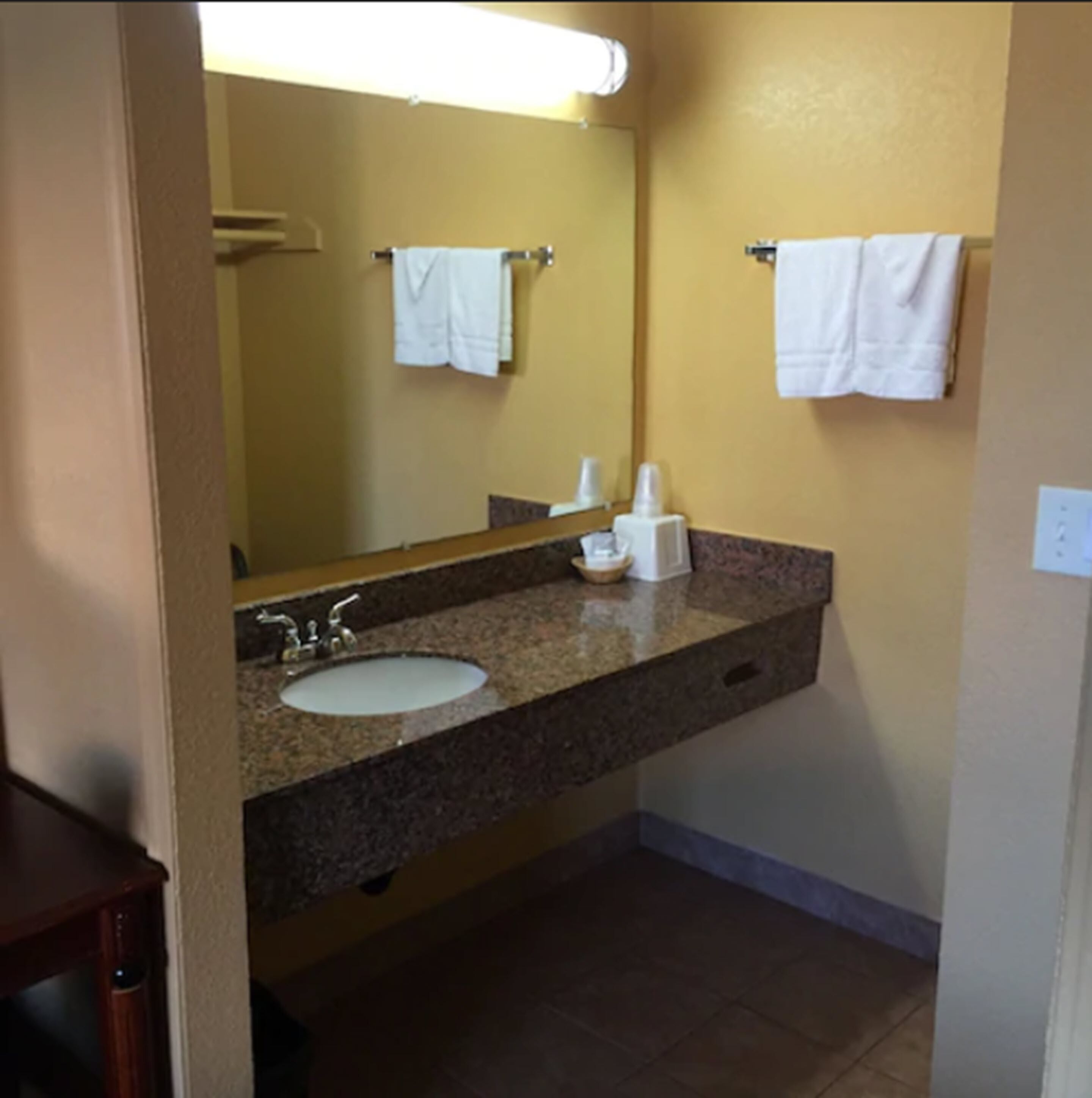 A bathroom with a sink, mirror, and two towels hanging on the wall.