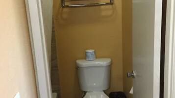 Un baño pequeño con inodoro, perchero y cubo de basura.