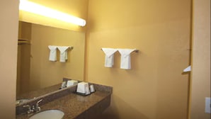 A bathroom with a sink, mirror, and towel racks. - National City Motel (National City)