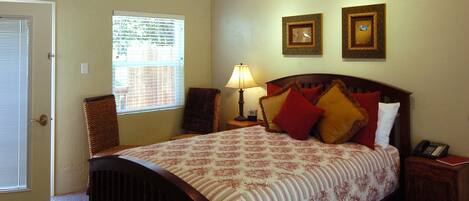 A bedroom with a bed, a ceiling fan, a window with blinds, a nightstand, and a lamp.