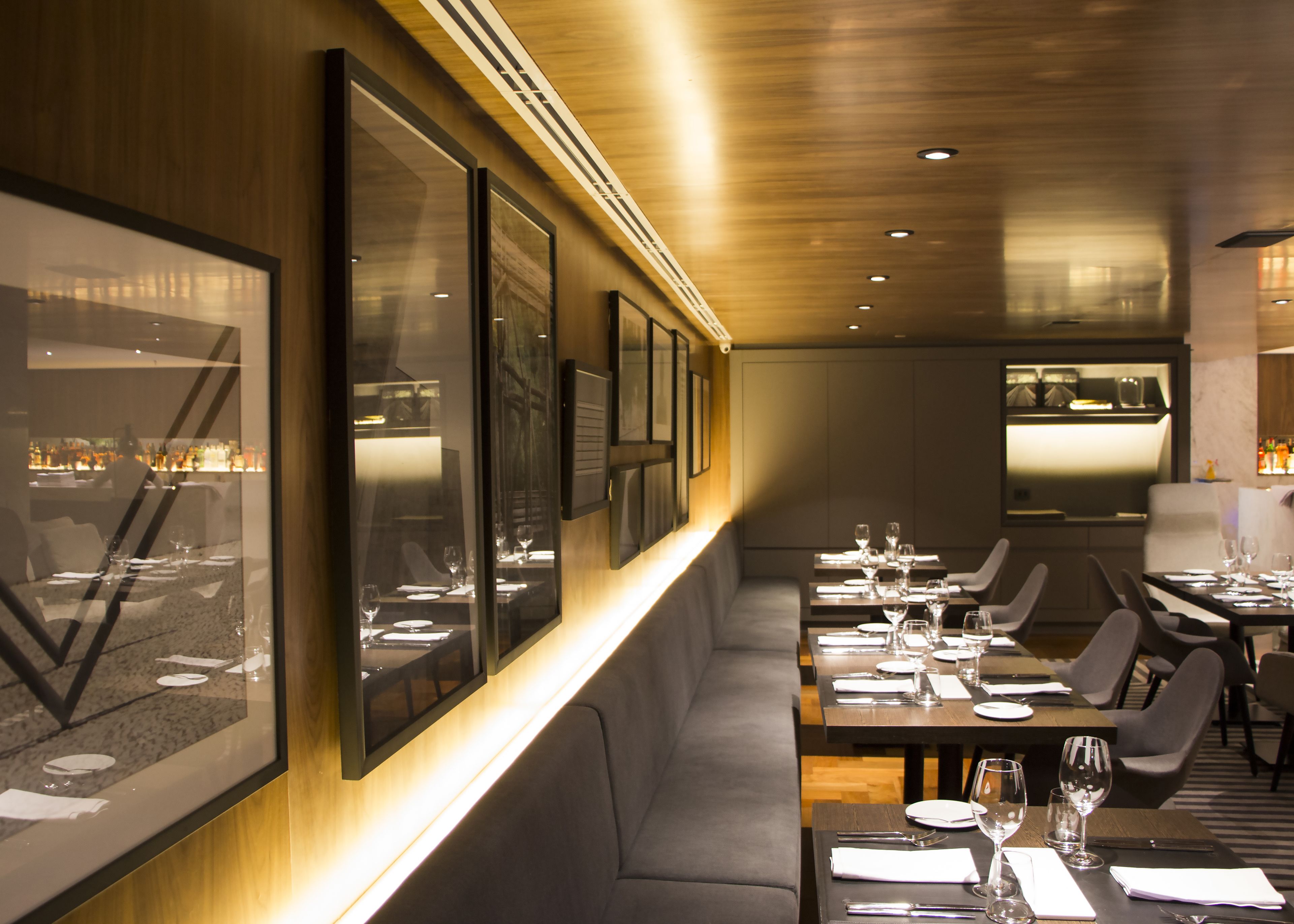Un restaurante moderno con mesas largas, asientos cómodos y obras de arte enmarcadas en las paredes.